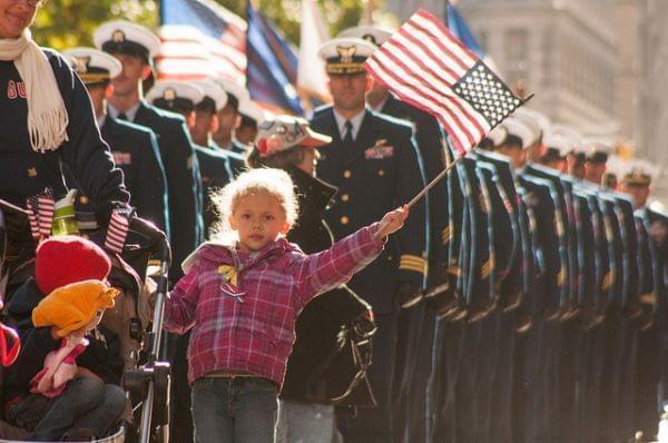 Blond little girl waving a small American flag at a Veteran's Day parade