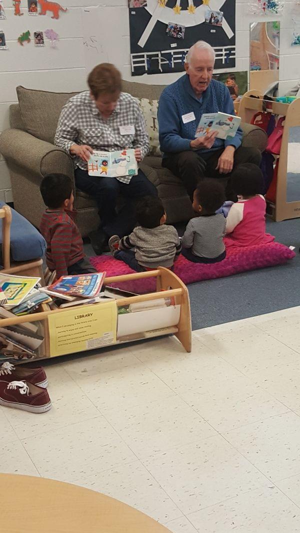 2 volunteers reading to small children