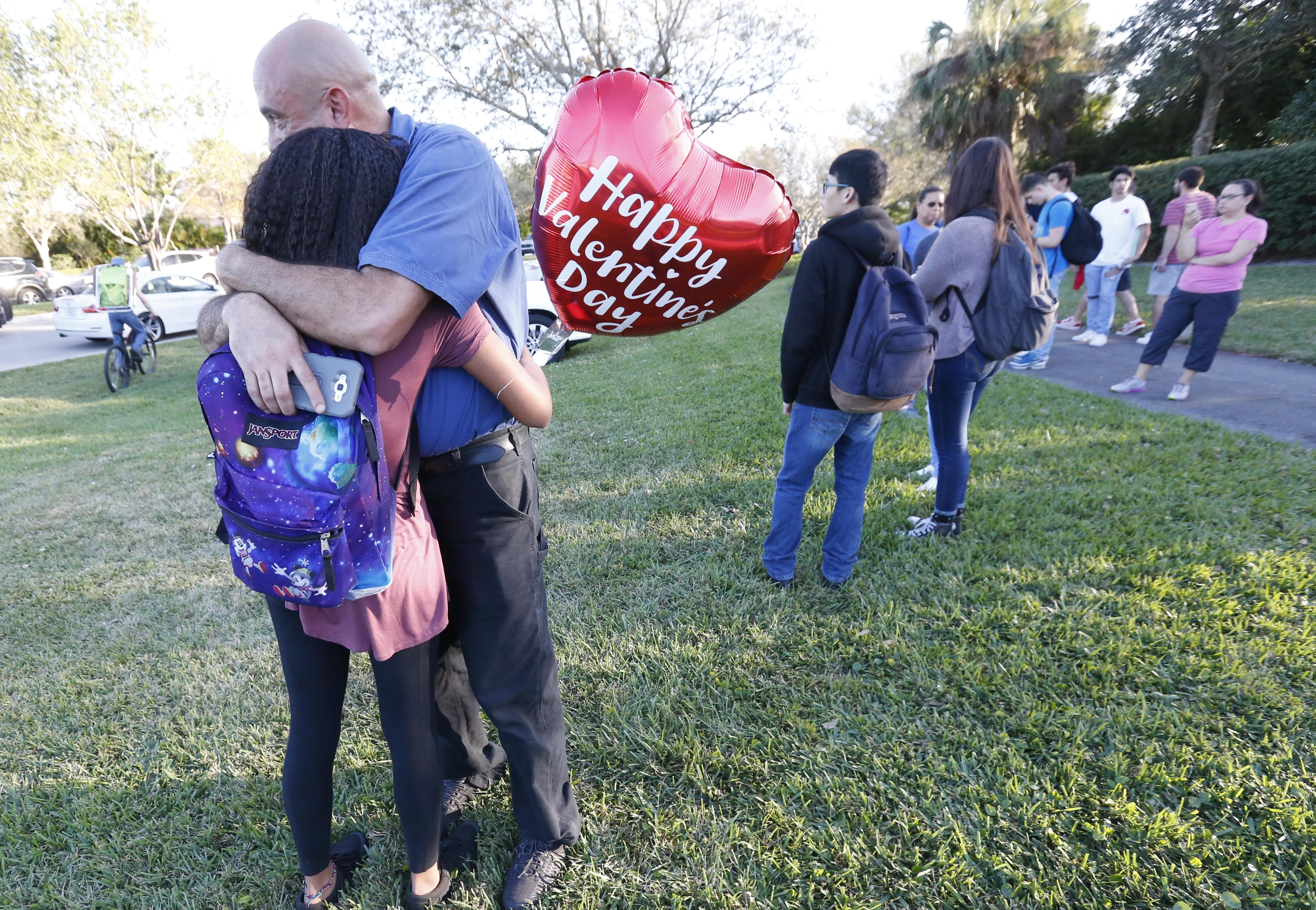 Family members, one of them holding a heart-shaped Valentine's Day balloon, embrace following a shooting at Marjory Stoneman Douglas High School, in Parkland, Florida on Wednesday.