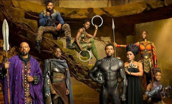 Main characters from the movie Black Panther standing together in African attire on the side of a mountain cliff.
