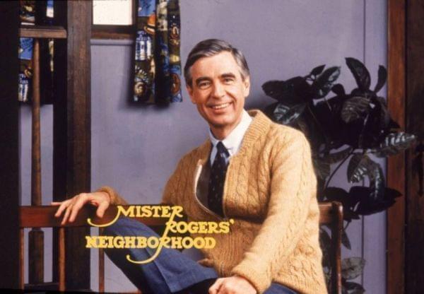 PBS icon, Fred Rogers seated with his toy trolley. 