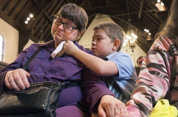 Nicholas Weible, offers his mom, Wendy Smith a tissue during the memorial service for his father, Christopher Weible, held at First Christian Church in Quincy, on April 20. 