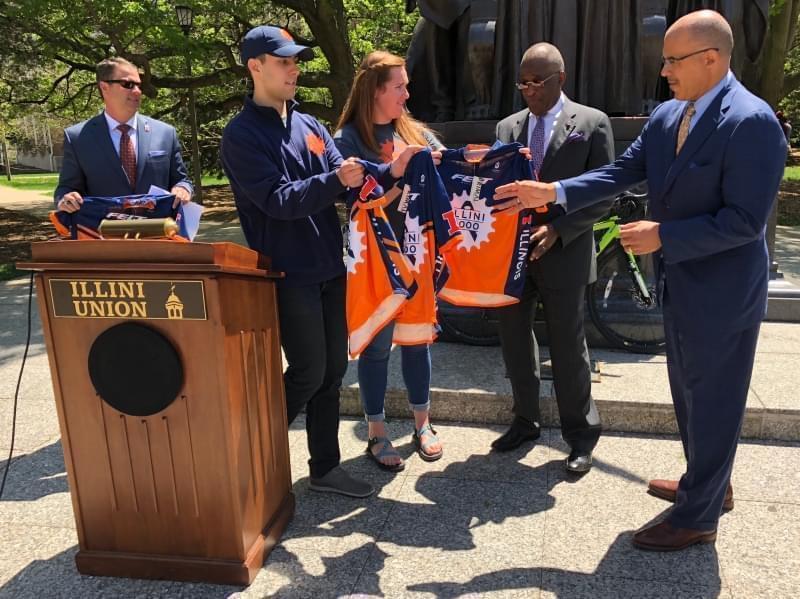 Illini 4000 Board Members present Chancellor Robert Jones and other campus administrators with bicycle gear for when they take part in one day of the Illini 4000 in the Champaign-Urbana area. 