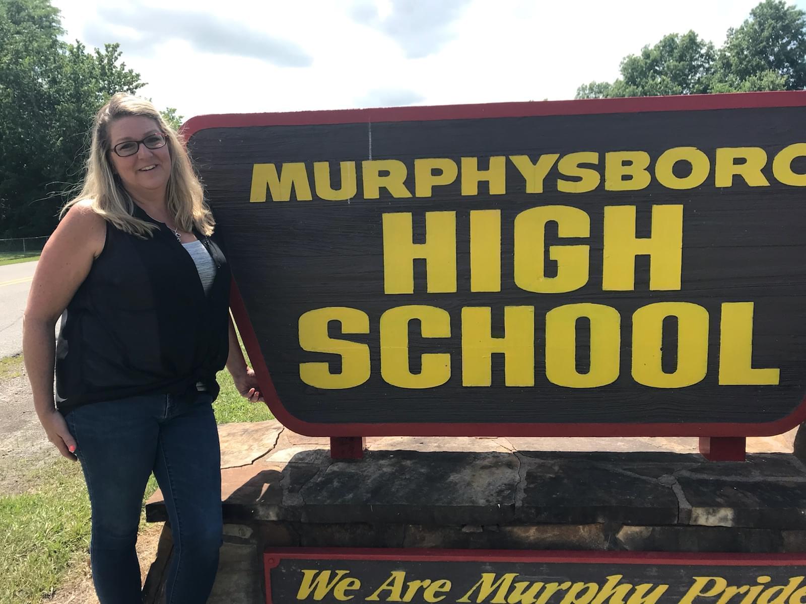 Murphysboro High School teacher Stacie Tefft stands next to a sign for the high school.