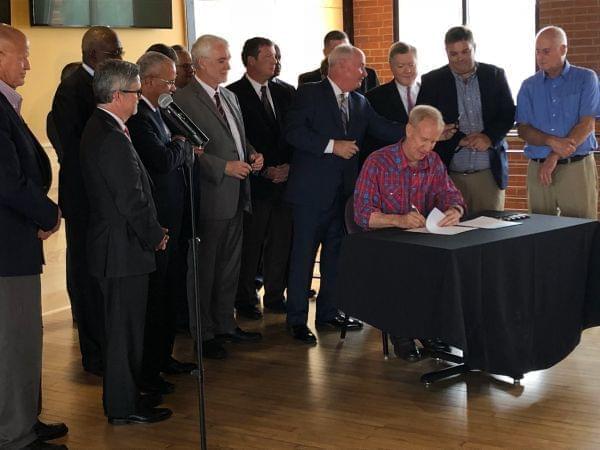 Gov. Bruce Rauner signs legislation surrounded by public university presidents at Papa Del's Pizza in Champaign. 
