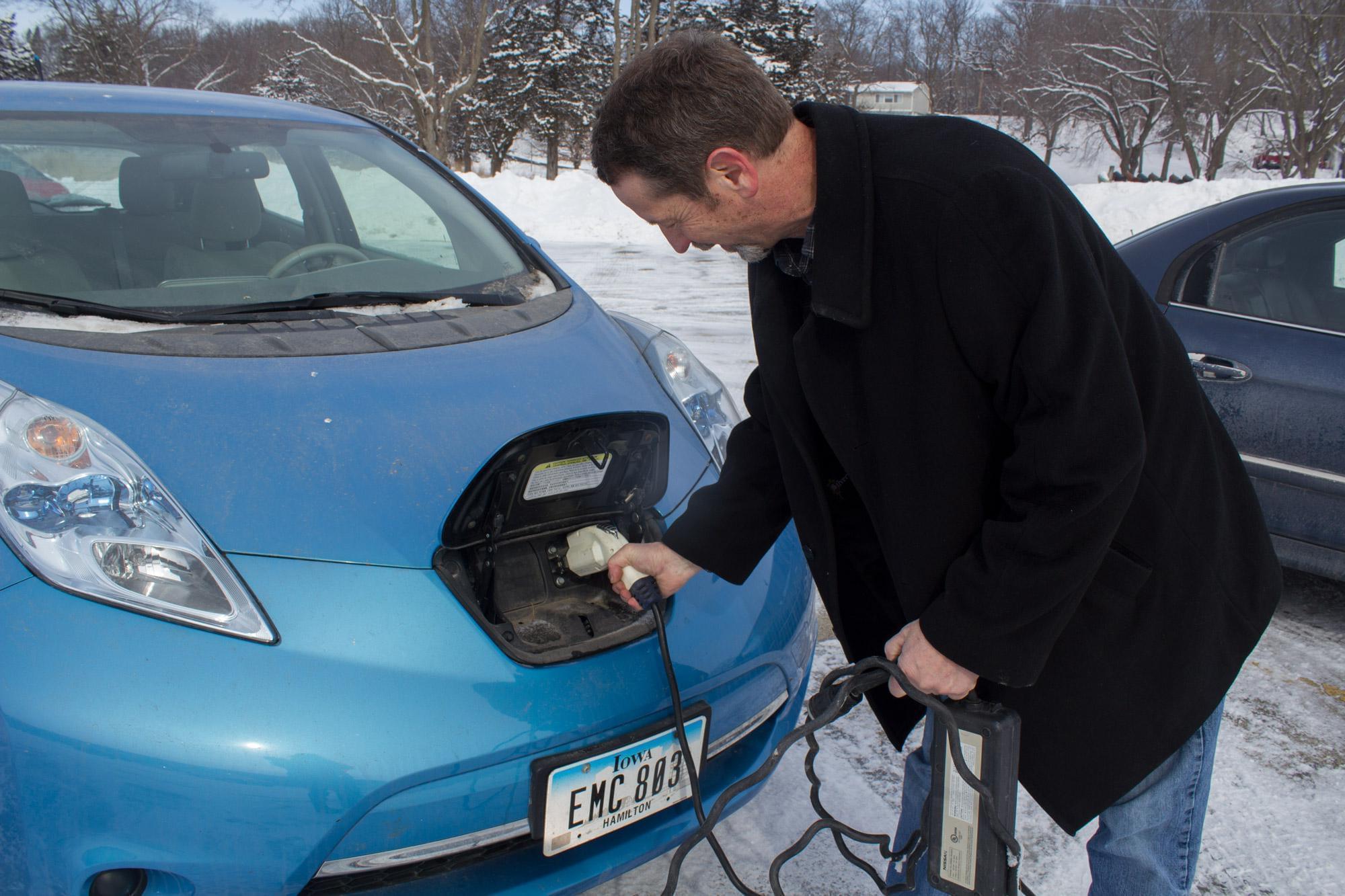 Nissan Leaf owner Rand Faaborg demonstrates how he attaches the electric cord to his car. The other end can be plugged into any standard 110-volt outlet.