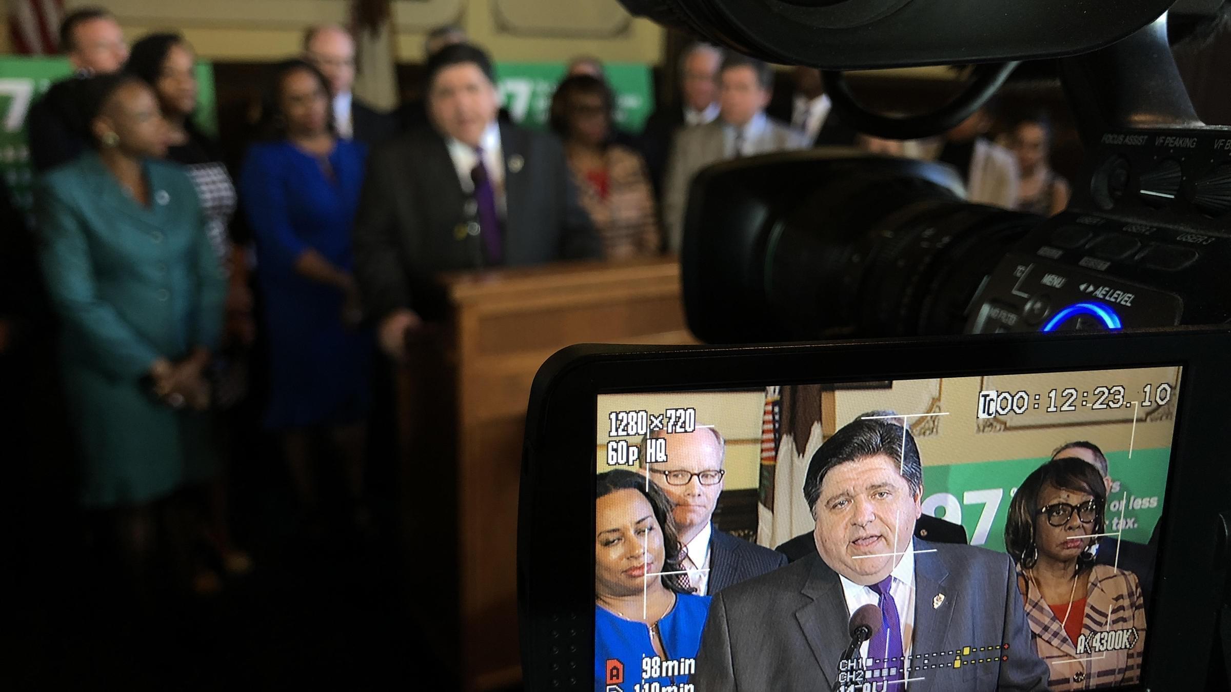 Gov. J.B. Pritzker, surrounded by Democratic lawmakers, spoke with reporters after the formal introduction of the constitutional amendment needed to advance his graduated income tax proposal.
