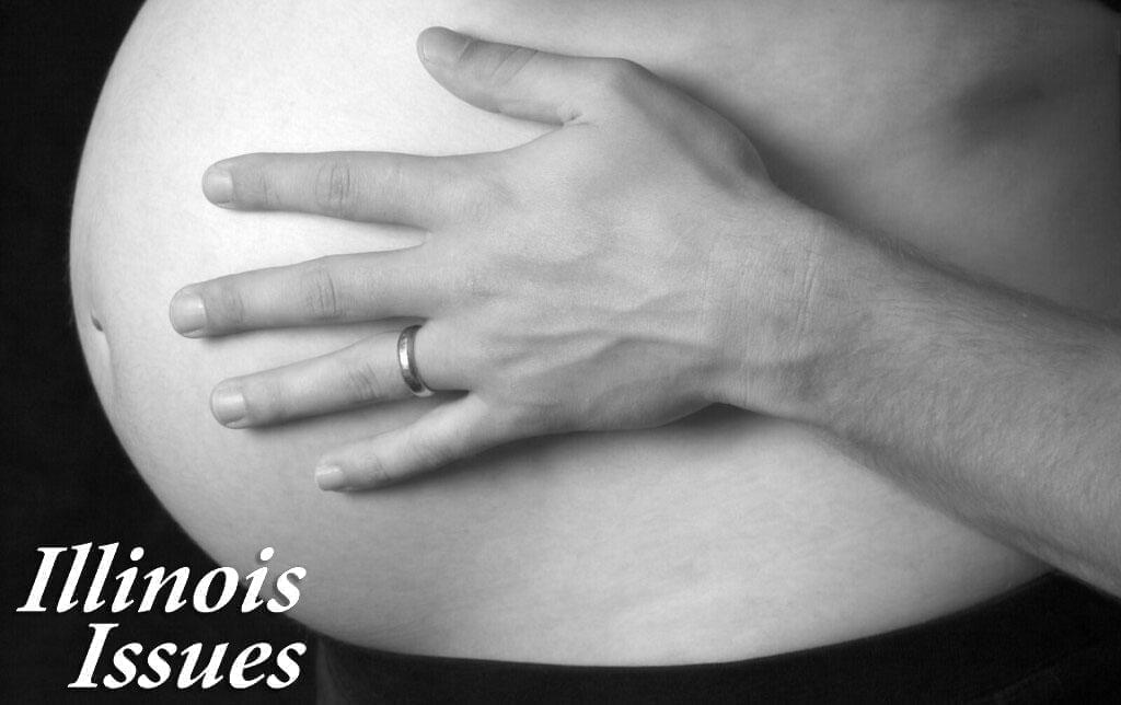 A pregnant woman holding her stomach.
