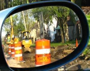 A roadside construction crew, seen through a rearview mirror.
