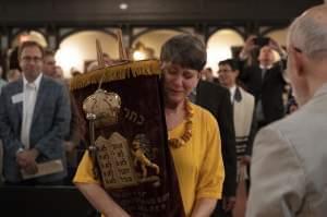 B'nai Sholom congregant Carla Gordon carries one of the sacred Torah scrolls through the synagogue during Saturday's deconsecration ceremony. The nearly 150-year-old synagogue closed its doors due to low membership and financial hardship.