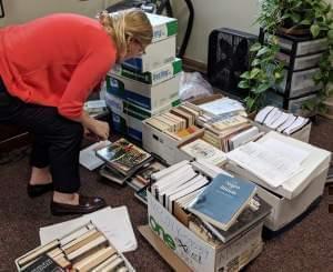 Holly Clingan crouches down to look through boxes of books removed from the EJP library at the Danville Correctional Center in an office on the University of Illinois campus. 
