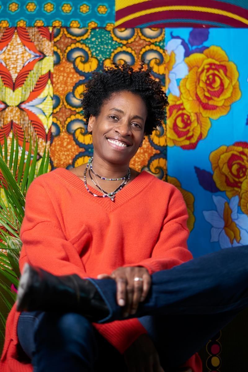 Jacqueline Woodson smiling and posing in front of a colorful background. 