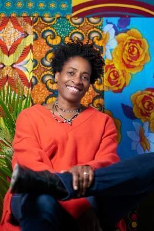 Jacqueline Woodson smiling and posing in front of a colorful background. 