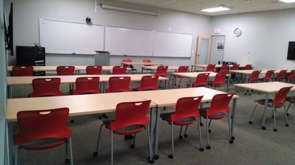 an empty classroom with red chairs