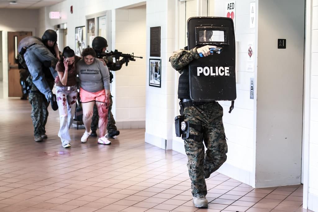 police officers lead "victims" through a hallway during an active shooter drill