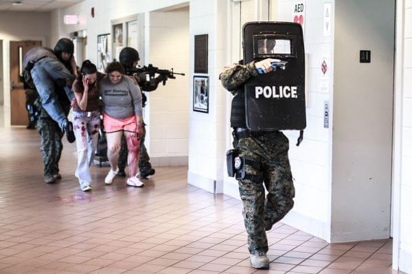 police officers lead "victims" through a hallway during an active shooter drill 