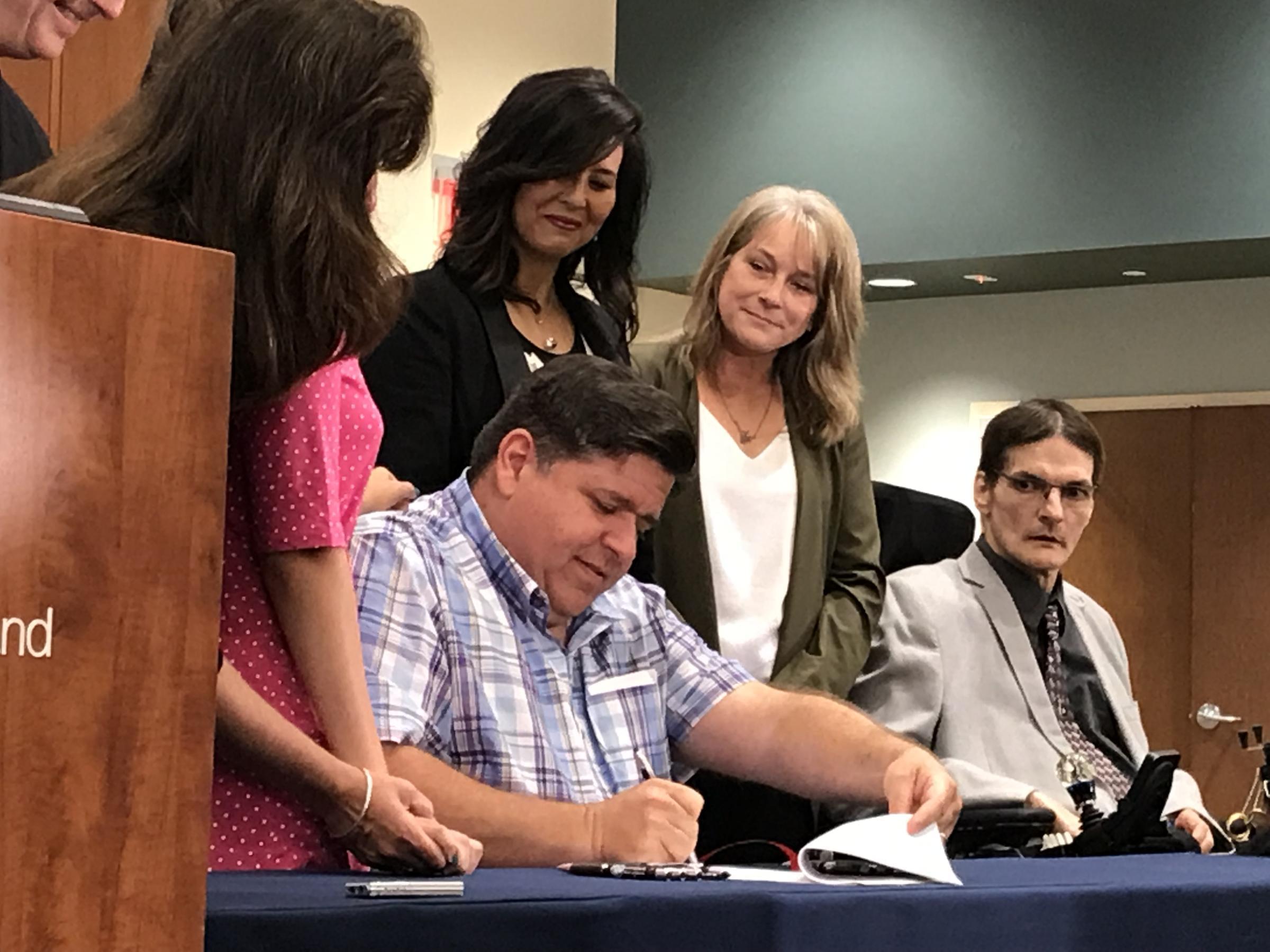 Gov. J.B. Pritzker, flanked by supporters and legislators, signs a law expanding school children's ability to use medical marijuana at school. The governor approved expansions to the Medical Marijuana program on Aug. 9. 