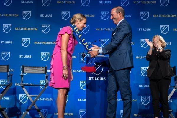 Major League Soccer Commissioner Don Garber drapes an MLS scarf that reads "St. Louis" over Carolyn Kindle Betz, who leads the ownership group for St. Louis' new professional soccer team. 