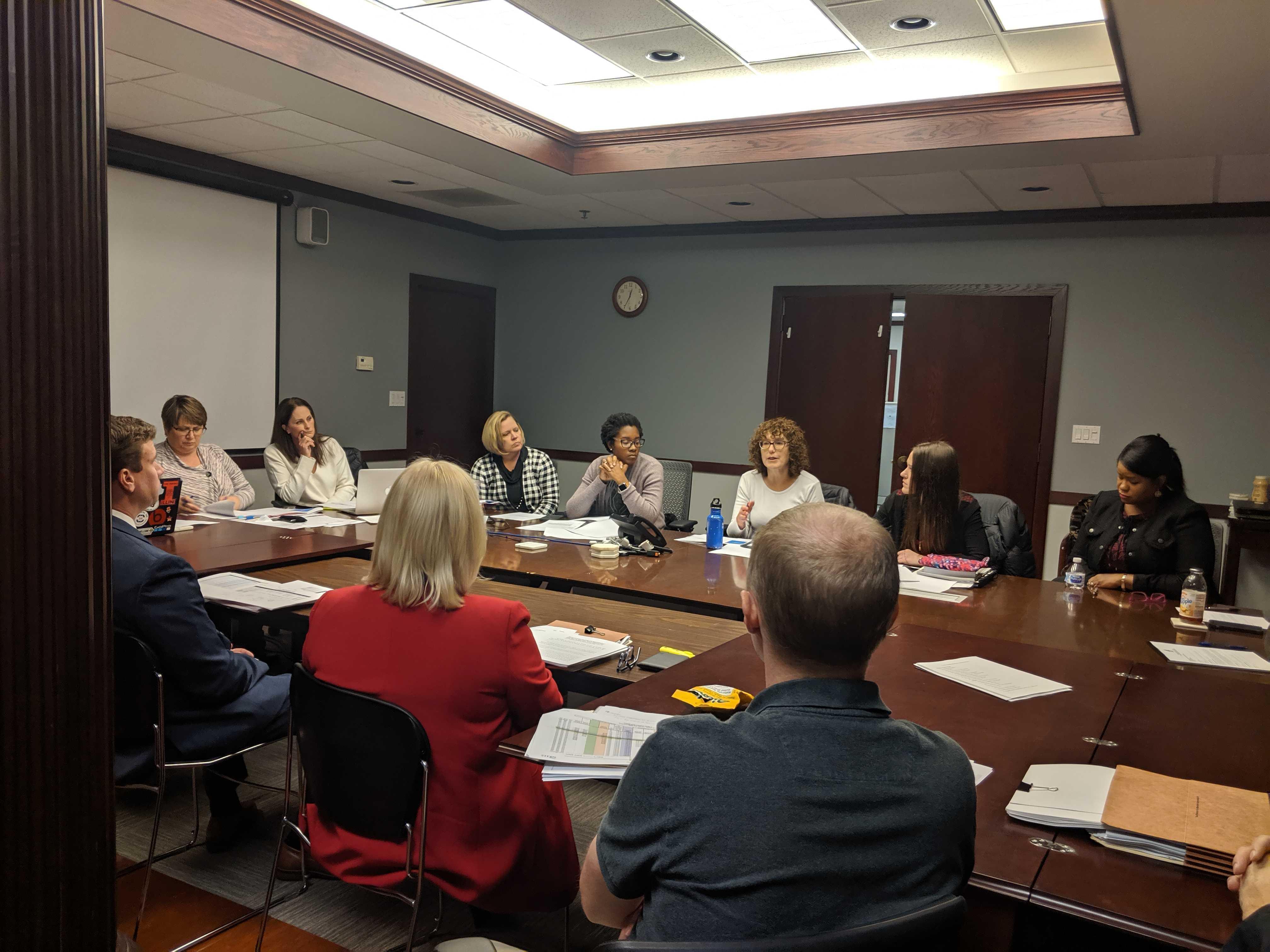 Champaign Unit 4 School Board members and other officials seated around a table in a conference room at one of the district's offices.