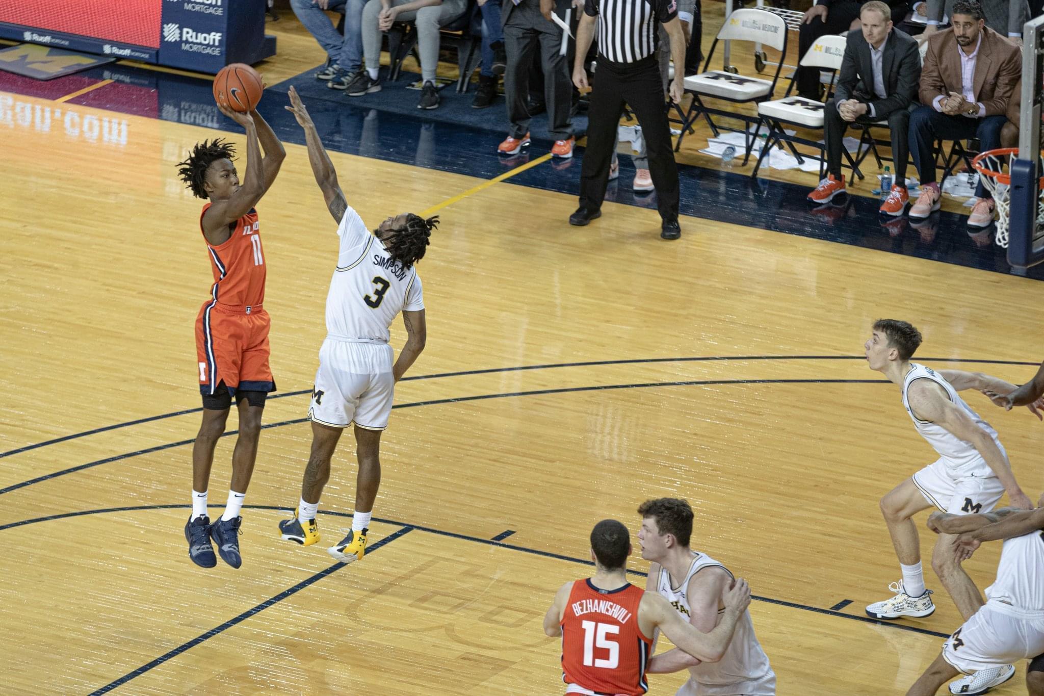 Ayo Dosunmu hits the game-winning shot over Michigan's Zavier Simpson in a 64-62 win on Saturday in Ann Arbor.
