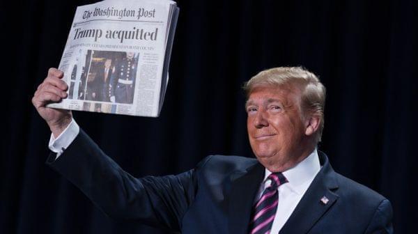 President Trump holds up Thursday's Washington Post with the headline "Trump acquitted." 