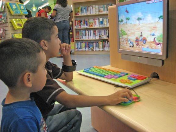 two kids behind a computer