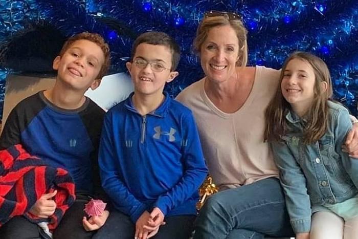 Lauren Kamnik and her three children pose for a photo seated in front of a blue background