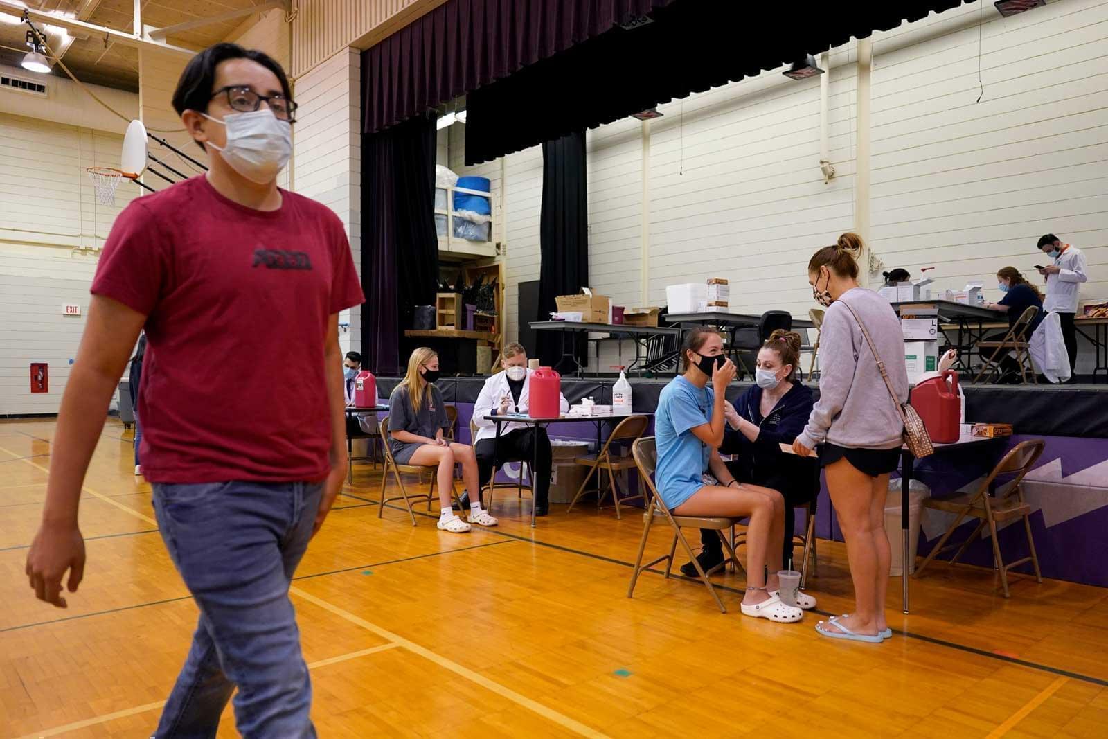 In this June 11, 2021, file photo, healthcare workers administrate a dose of the Pfizer COVID-19 vaccine to students during a vaccination clinic hosted by Jewel Osco in Wheeling, Ill. The latest alarming coronavirus variant, the delta variant, is exploiting low global vaccination rates and a rush to ease pandemic restrictions, adding new urgency to the drive to get more shots in arms and slow its supercharged spread.
