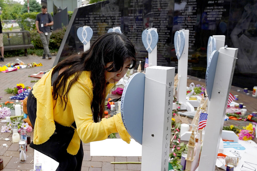 Yesenia Hernandez, granddaughter to Nicolas Toledo, who was killed during Monday's Highland Park., Ill., Fourth of July parade, writes on a memorial for Toledo along with the six others who lost their lives in the mass shooting, Wednesday, July 6, 2022, in Highland Park.