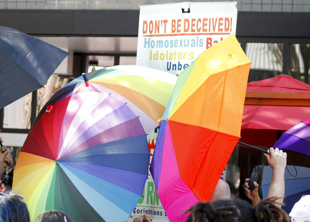 A sign-carrying anti-gay protester is surrounded by a sea of Pride umbrellas during the Pride parade in Winston-Salem, N.C., June 18, 2022. Hateful references to gays, lesbians and other LGBTQ Americans on social media surged following Florida's adoption of a law restricting how teachers can talk about sexual orientation with younger students.