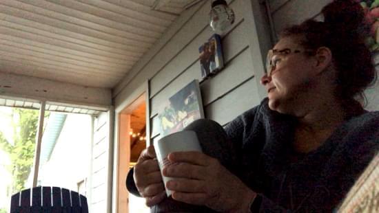 Angie Rouley sits on her front porch during a thunderstorm.