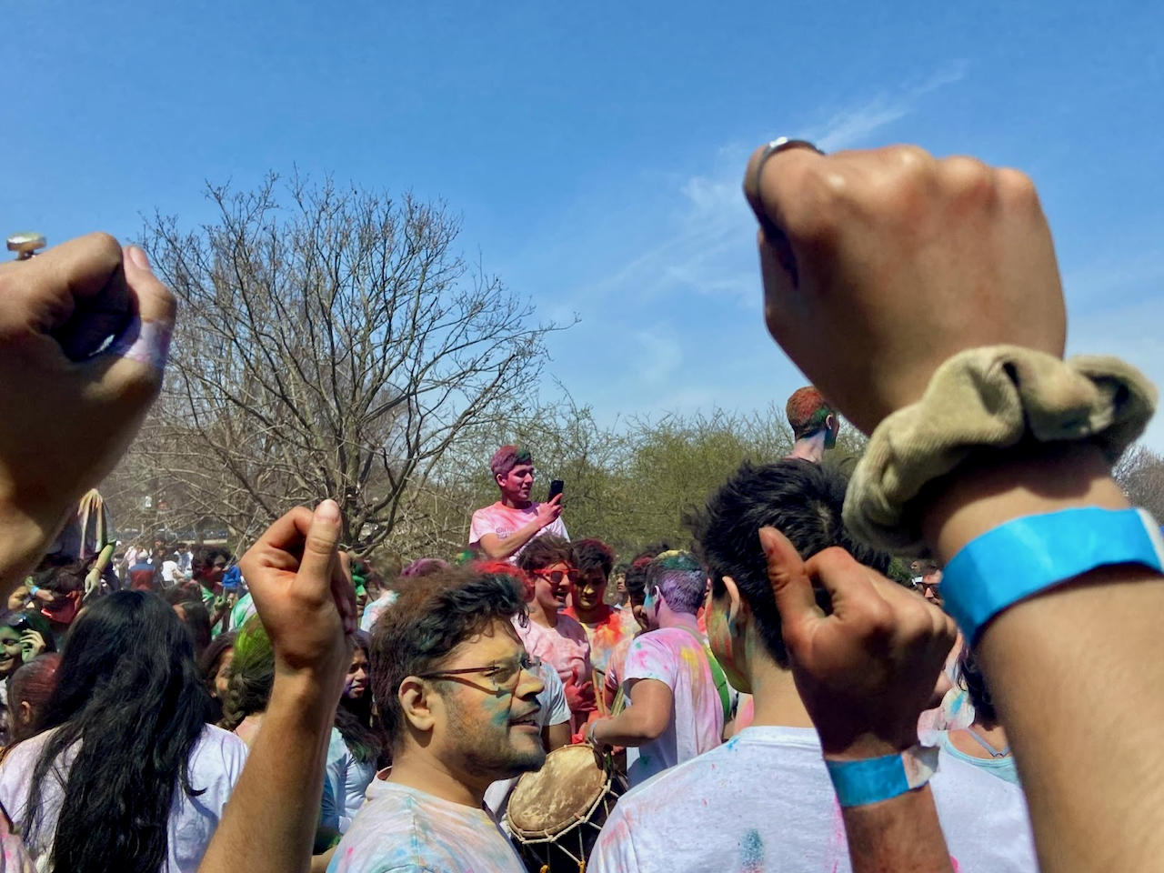 Students bang drums and pump their fists at the Holi celebration. Holi is a Hindu festival that celebrates the arrival of spring, among other themes. 