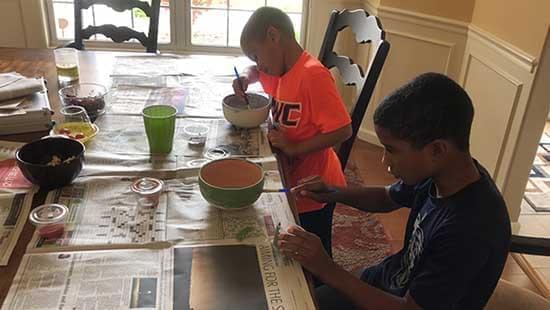 Ronald Baker's sons paint bowls in an impromptu art class