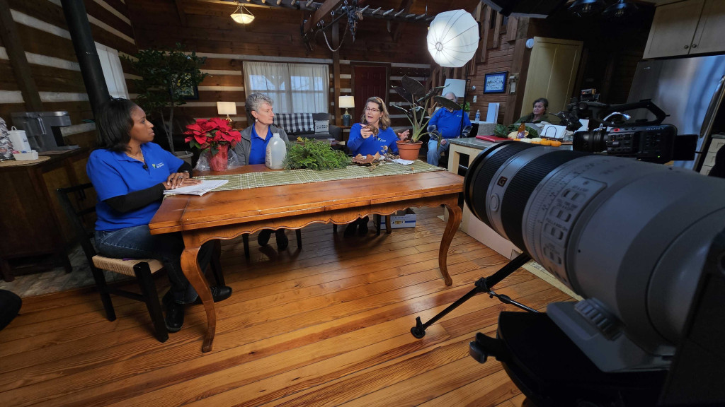 The panelists of Mid American Gardener discuss poinsettias with Tinisha Spain around a large wooden table