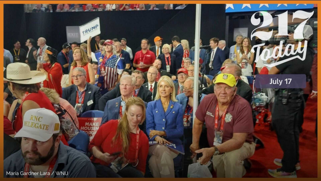 Rep. Mary Miller (R-IL13) sits at the 2024 RNC convention in the center of frame wearing a blue polo shirt.