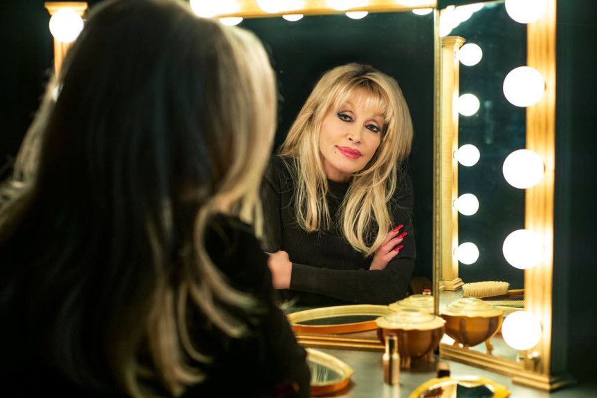 Dolly Parton looking at herself in a mirror
