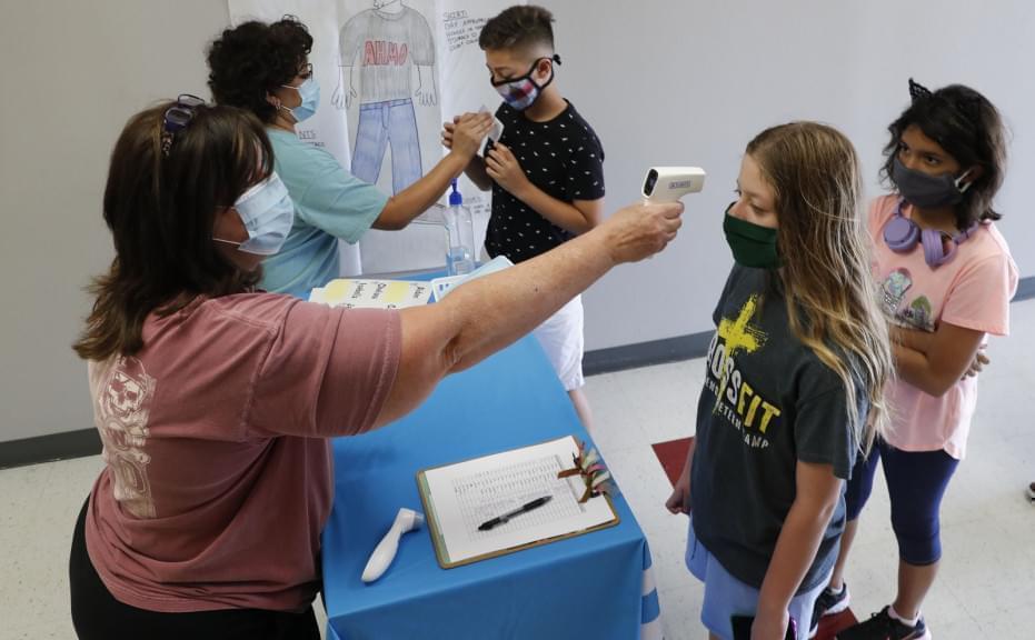 In this July 14, 2020, file photo, amid concerns of the spread of COVID-19, science teachers Ann Darby, left, and Rosa Herrera check-in students before a summer STEM camp at Wylie High School in Wylie, Texas. Schools and camps across the county are making plans to help kids catch up academically this summer after a year or more of remote learning for many of them.