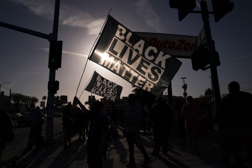 People hold Black Lives Matter flags at the intersection of Florence and Normandie Avenues, Tuesday, April 20, 2021, in Los Angeles, after a guilty verdict was announced at the trial of former Minneapolis police Officer Derek Chauvin for the 2020 death of George Floyd.