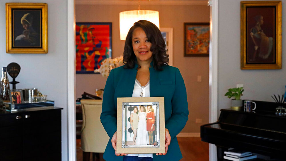 Robin Rue Simmons, alderwoman of Evanston's 5th Ward poses for a portrait holding a photograph of her mother, aunt and grandmother in her home in Evanston, Ill., Friday, April 9, 2021. The Chicago suburb is preparing to pay reparations in the form of housing grants to Black residents who experienced housing discrimination. Simmons, a fourth generation Black resident, spearheaded the effort after studying racial disparity data, which shows the average income of Black families in Evanston is $46,000 less than that of white families.