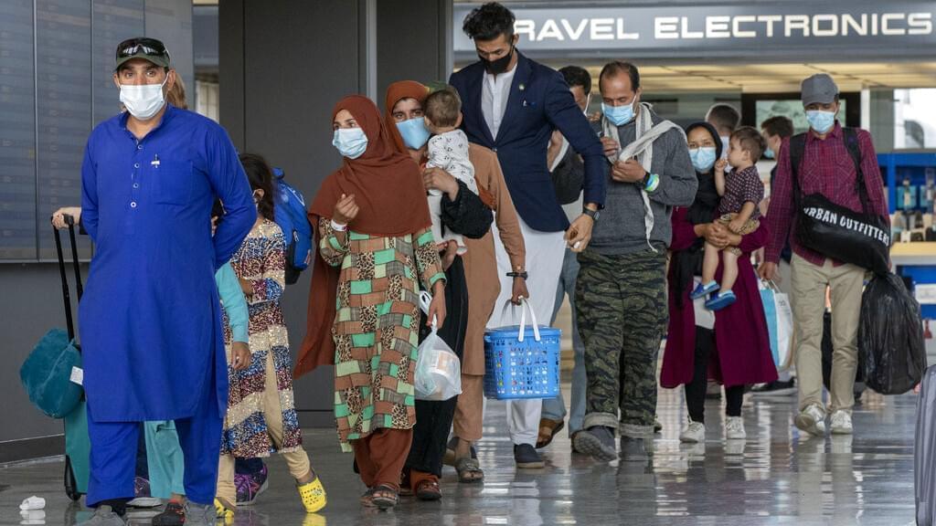 In this Tuesday, Aug. 31, 2021, file photo, families evacuated from Kabul, Afghanistan, walk through the terminal to board a bus after they arrived at Washington Dulles International Airport, in Chantilly, Va. U.S. religious groups of many faiths are gearing up to assist the thousands of incoming refugees.