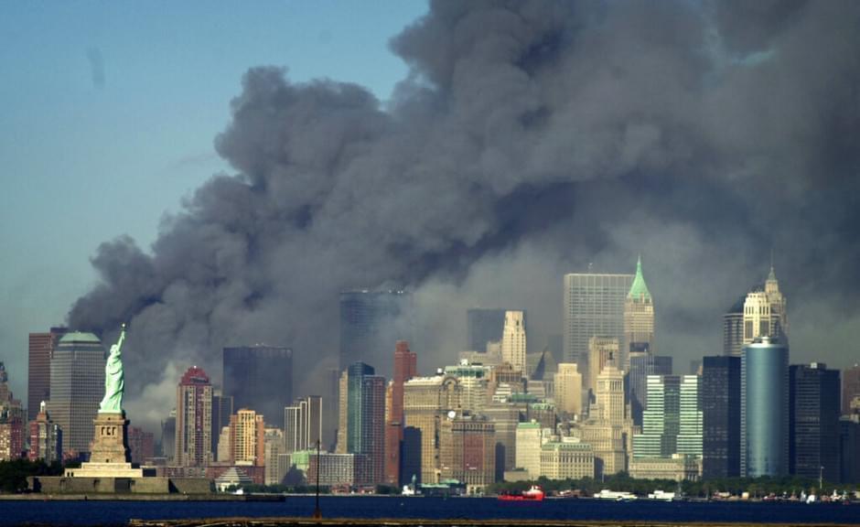 Thick smoke billows into the sky from the area behind the Statue of Liberty, lower left, where the World Trade Center was, on Tuesday, Sept. 11, 2001.