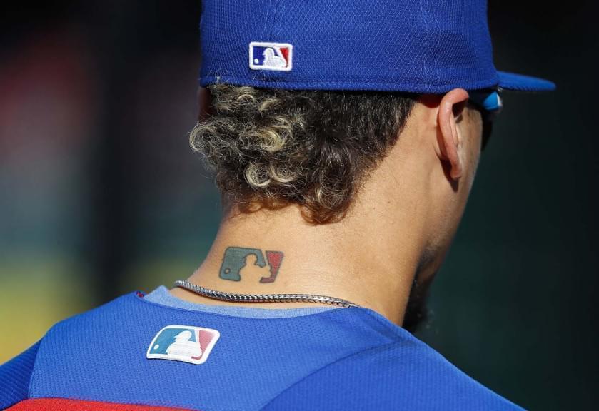 FILE - Then-Chicago Cubs' Javier Baez sports an MLB logo tattoo and logos on his hat and jersey as he waits to take batting practice before Game 2 of baseball's National League Division Series against the Washington Nationals at Nationals Park, Saturday, Oct. 7, 2017, in Washington. MLB owners have locked out players, ending the sport’s labor peace at more than 26 1/2 years.