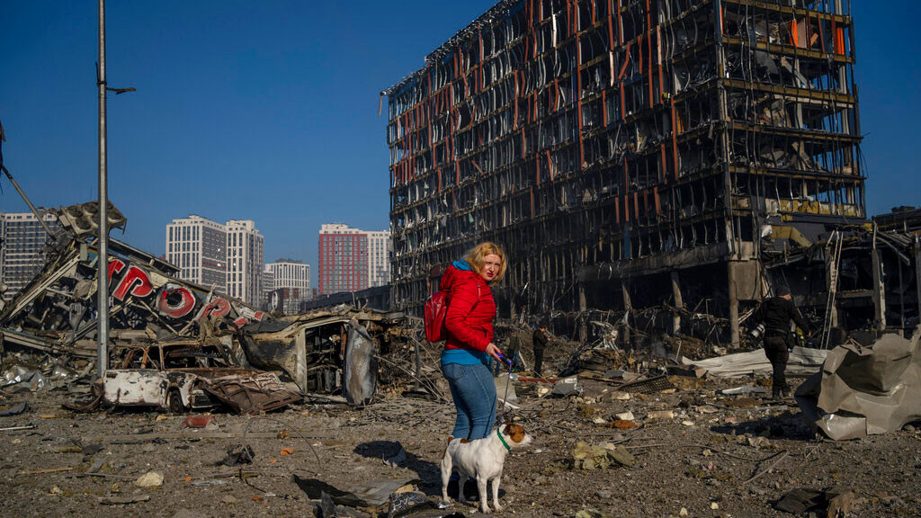Irina Zubchenko walks with her dog Max amid the destruction caused after shelling of a shopping center, in Kyiv, Ukraine, Monday, March 21, 2022.