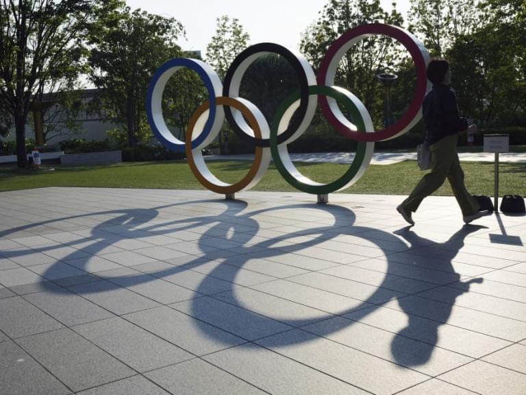 A woman walks by the Olympic Rings near the National Stadium in Tokyo Wednesday, June 9, 2021. Roads were being closed off since last Tuesday around Tokyo Olympic venues, including the new $1.4 billion National Stadium where the opening ceremony is set for July 23.