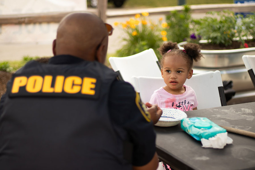 Champaign Chief of Police, Timothy T. Tyler, making bracelets with a kid at the 