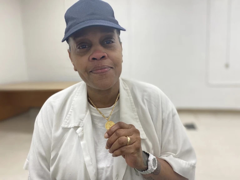 Pat Johnson holds up a medallion with an image of Jesus in Logan Correctional Center on April 18, 2022. The medallion was given to Johnson by his family. Johnson is incarcerated for a murder committed by his then-partner and abuser. The little known “theory of accountability” law allows people to be punished for the acts of another person.