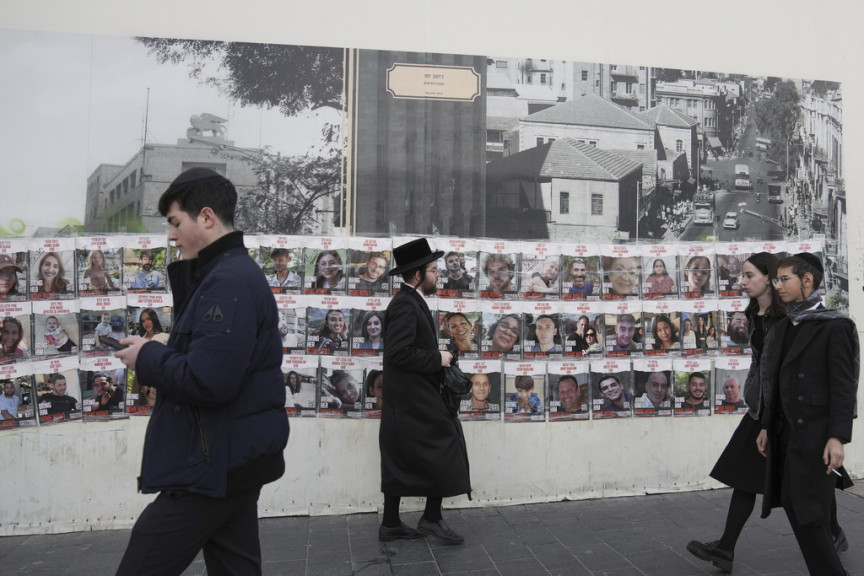 People pass by a wall with photos of about 240 hostages who were abducted during the Oct. 7, Hamas attack on Israel. in Jerusalem on Tuesday, Nov. 28, 2023.