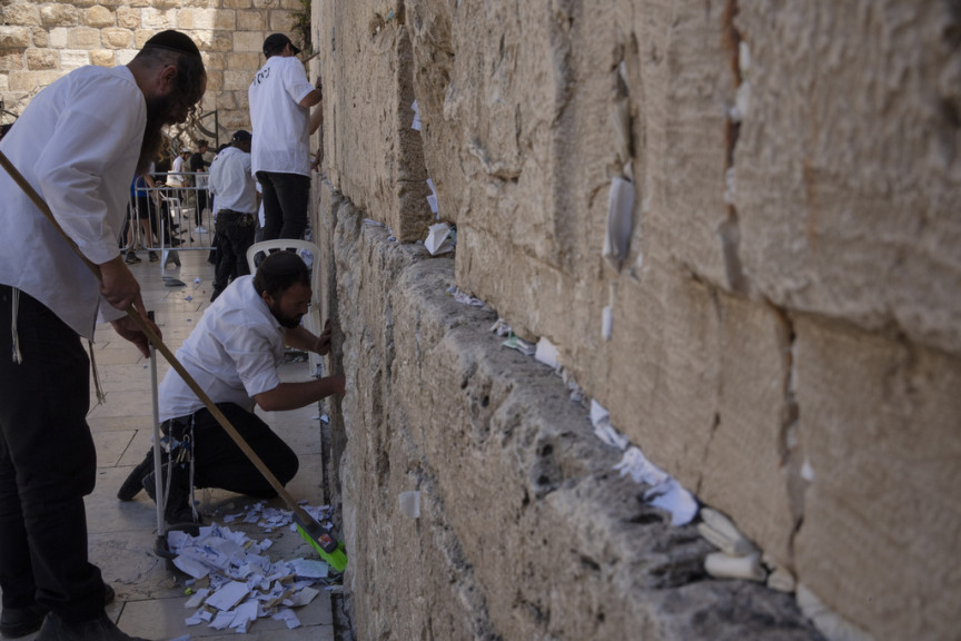 Workers remove prayer notes left into crevices of ancient stones by visitors at Western Wall, the holiest site where Jews can pray, ahead the holiday of Passover, in Jerusalem's Old City, Tuesday, April 16, 2024. The notes are buried in a nearby cemetery according to Jewish tradition. 