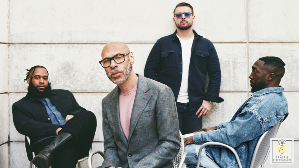 The four members of the Joshua Redman Quartet. Three are sitting relaxed in chairs, and one is leaning against a wall wearing sunglasses. 
