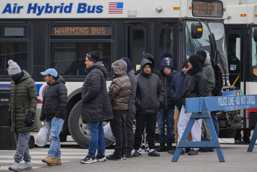 Migrants stand in line to receive food from the nonprofit Chi-Care Thursday, Jan. 11, 2024, in Chicago. In the city of Chicago's latest attempt to provide shelter to incoming migrants, several CTA buses were parked in the area of 800 South Desplaines Street to house people in cold winter weather.